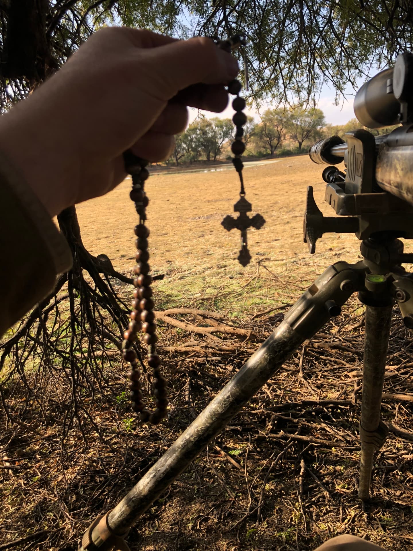A retreatant holds a rosary beside his rifle at dawn, praying before the hunt