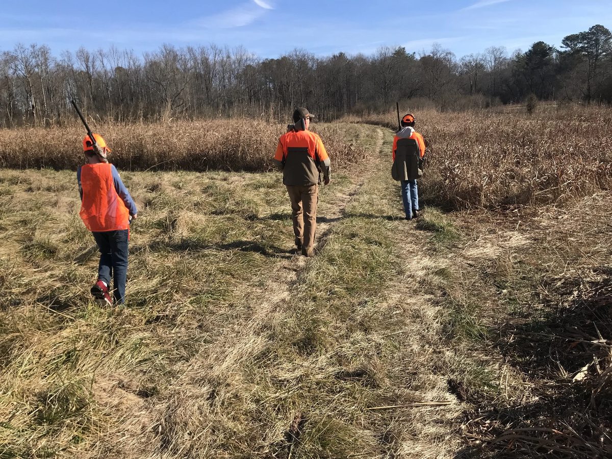 A father and his sons walking a field together on a St. Hubert Foundation hunt